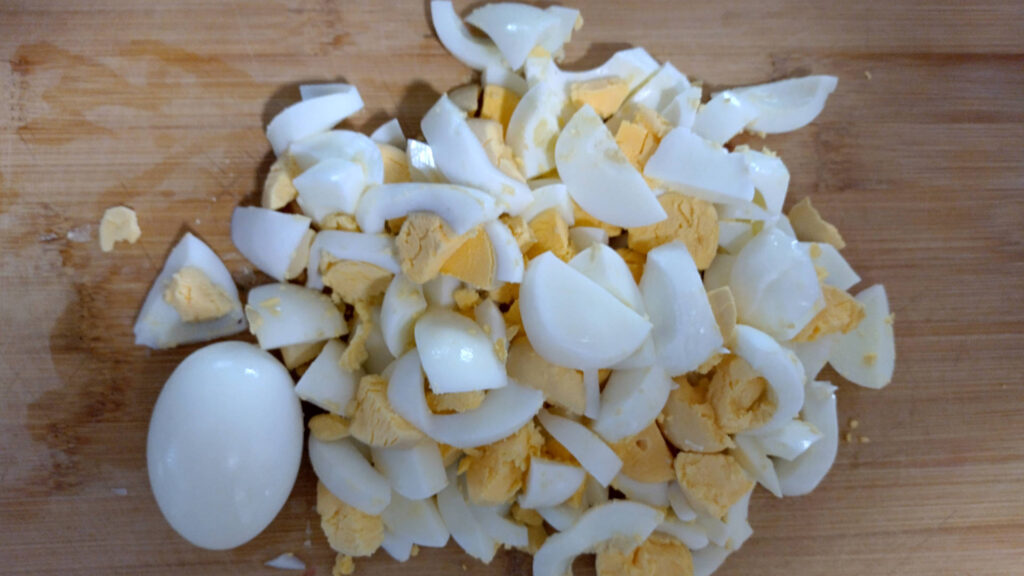 Boiled eggs copped on a board, one whole egg 